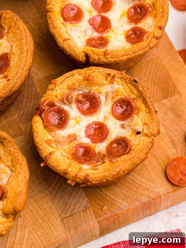 Crispy Oven-Roasted Potatoes with Garlic and Herbs 10 Golden crusted pizza cupcakes on a wooden cutting board with pepperoni scattered around the table.