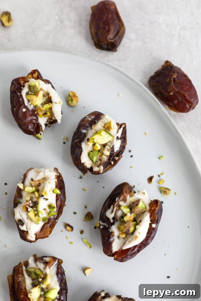 Savory Stuffed Dates: Flavorful Appetizer Recipes for Entertaining 10 Dates stuffed with cream cheese and topped with pistachios, hemp hearts, and chia seeds on white plate