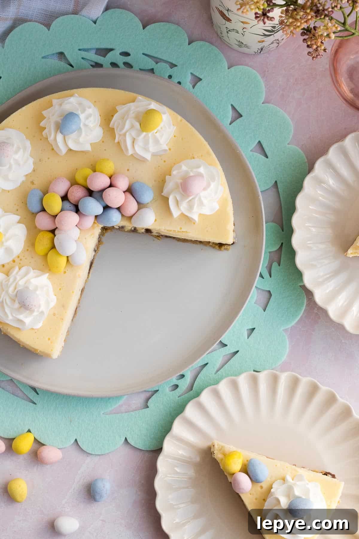 top view of an Easter egg cheesecake with 2 slices cut out and on scalloped plates to the side