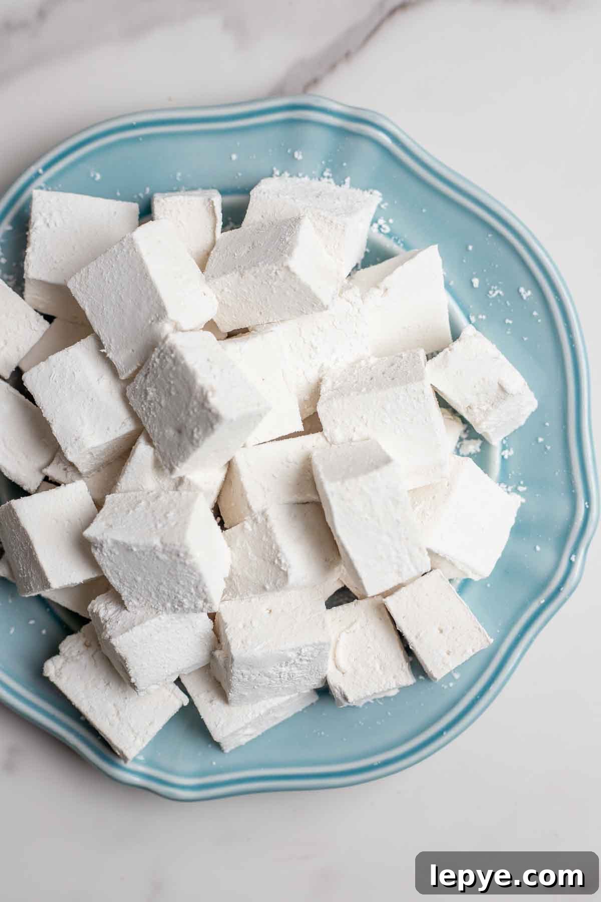 How to Make Homemade Marshmallows from Scratch 12 Overhead photo of homemade marshmallows stacked on a blue plate.