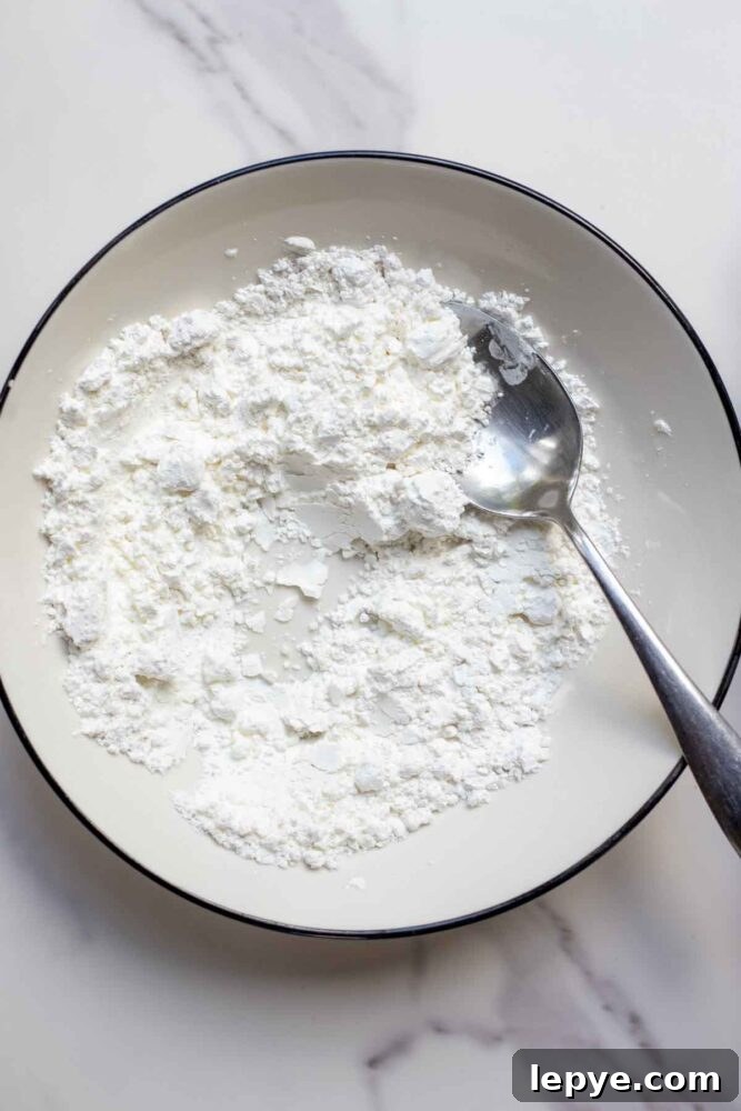 How to Make Homemade Marshmallows from Scratch 7 Cornstarch and powdered sugar in a bowl with a spoon.