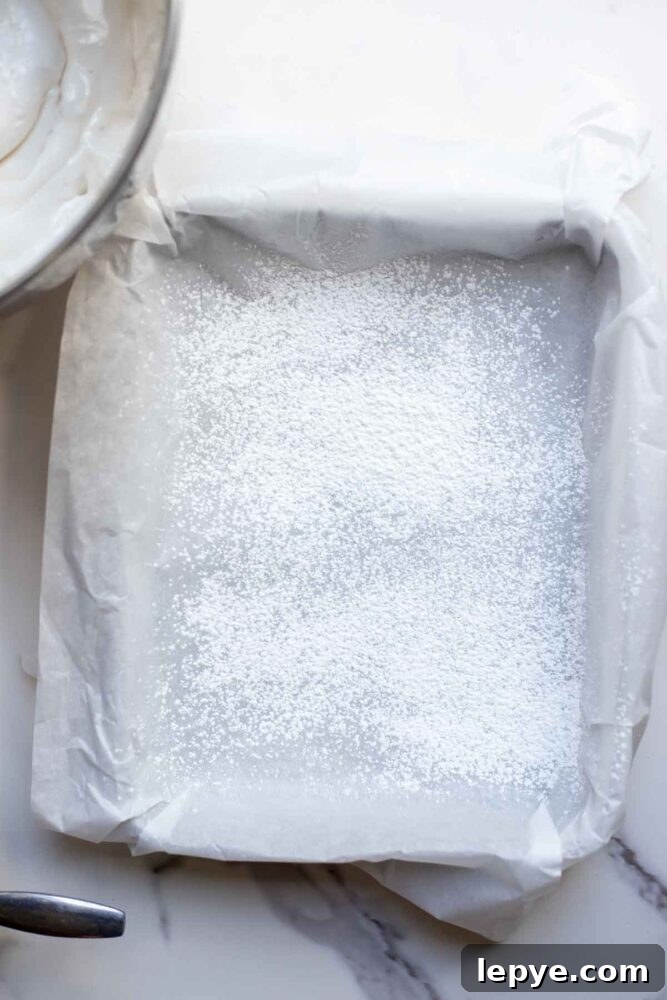 How to Make Homemade Marshmallows from Scratch 8 A pan lined with parchment paper and sprinkled with powdered sugar and cornstarch.
