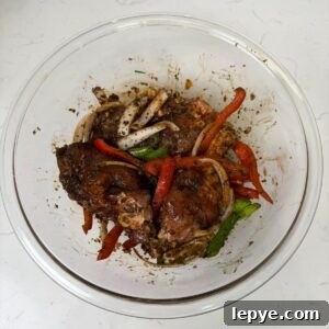 Authentic Jamaican Brown Stew Chicken Recipe 5 Chicken in a bowl with marinate, onions and peppers.