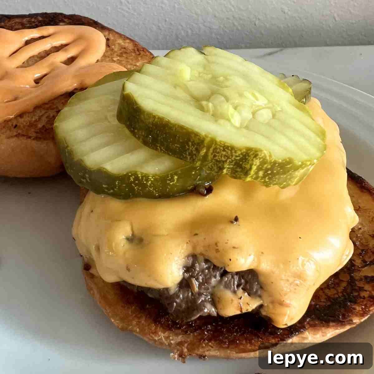 Blackstone Burger Cooking Guide: Tips for Juicy, Crispy Patties 2 Perfectly cooked burgers on a Blackstone with cheese.