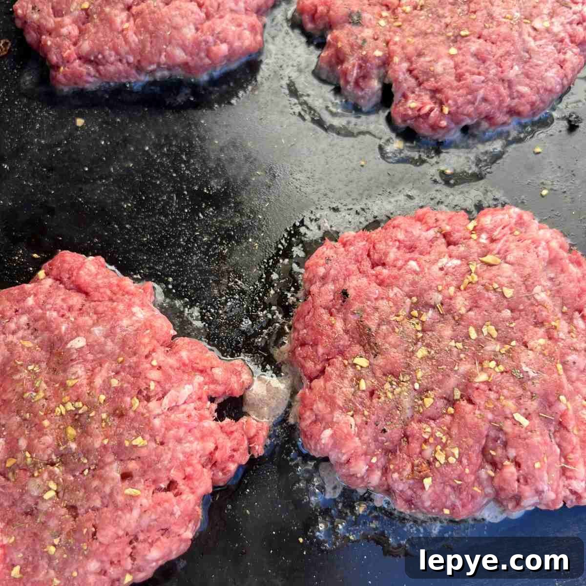 Blackstone Burger Cooking Guide: Tips for Juicy, Crispy Patties 4 Raw burgers on Blackstone griddle.
