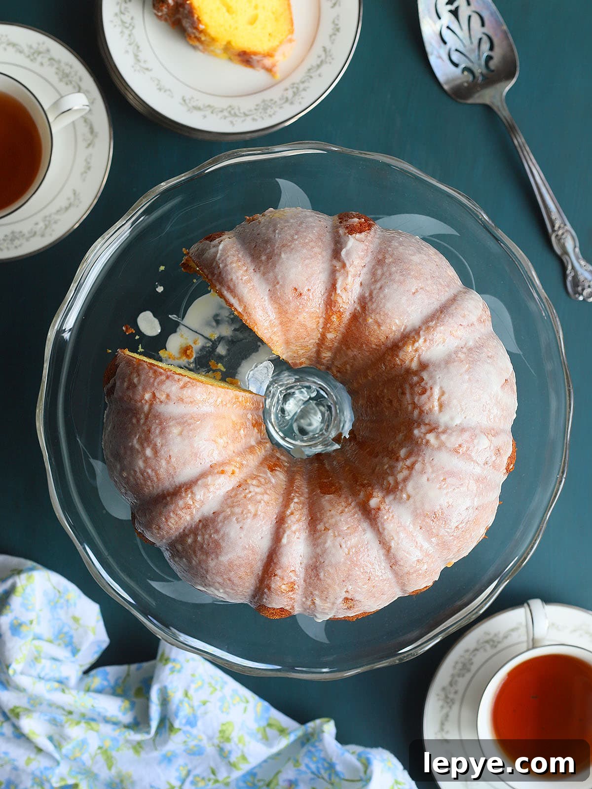 Apricot nectar cake on a clear glass cake pedestal with one slice removed.