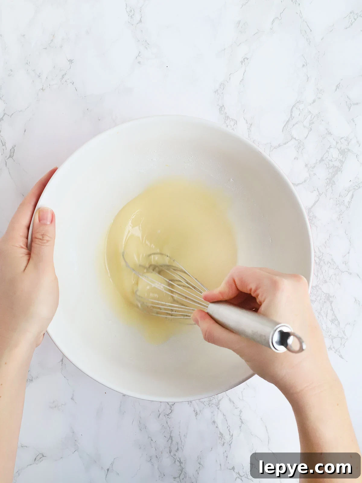 Hands whisking together the glaze ingredients