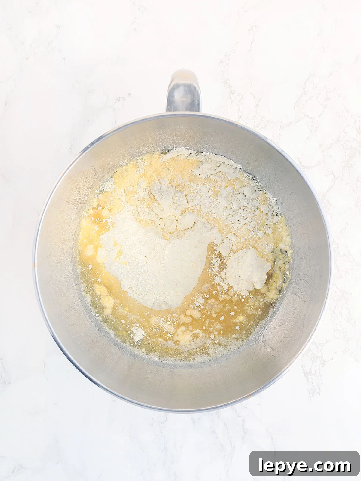 Lemon cake mix, apricot nectar and oil unmixed in a metal mixing bowl.