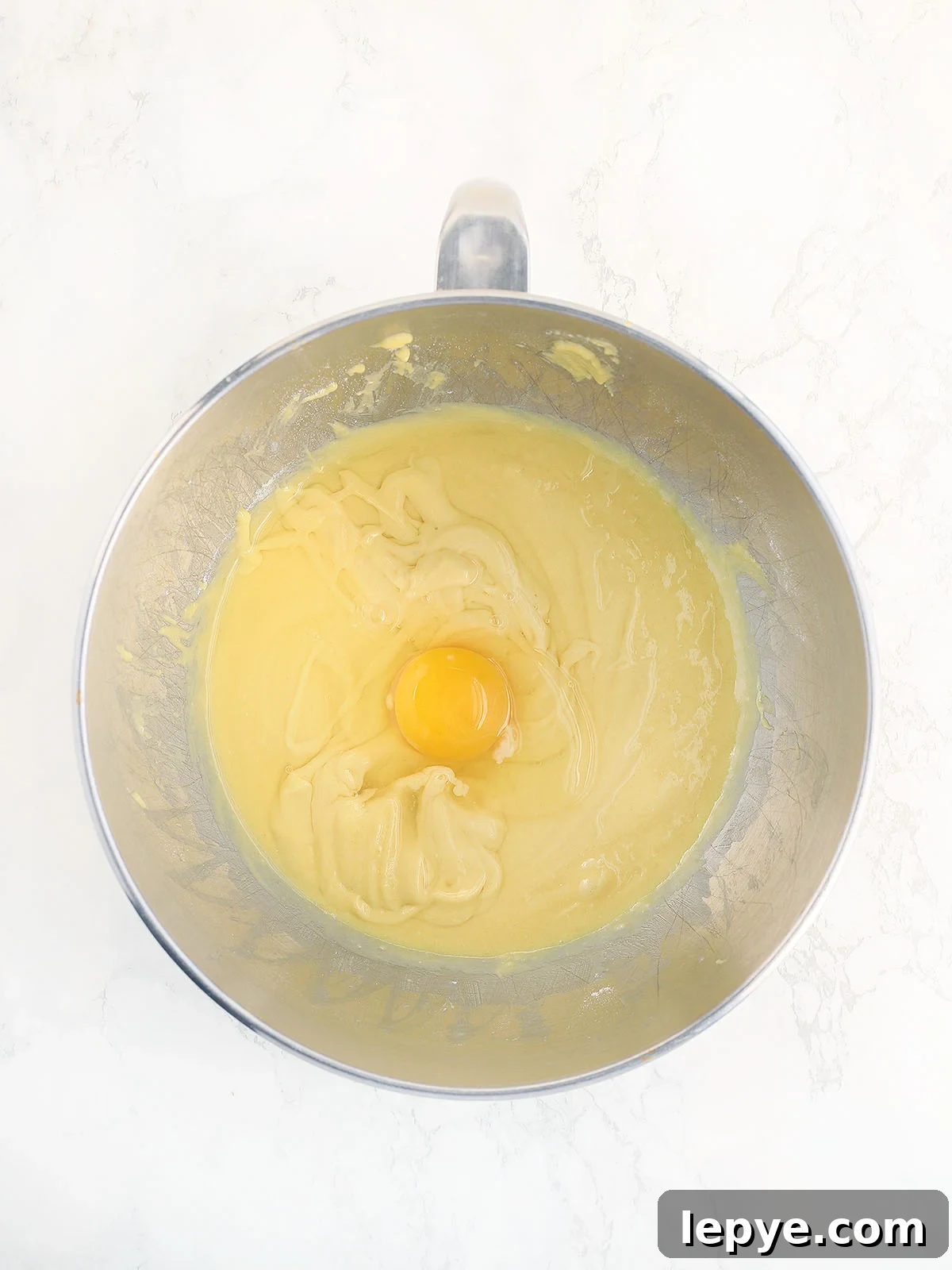 Adding the eggs one at a time to the cake batter.