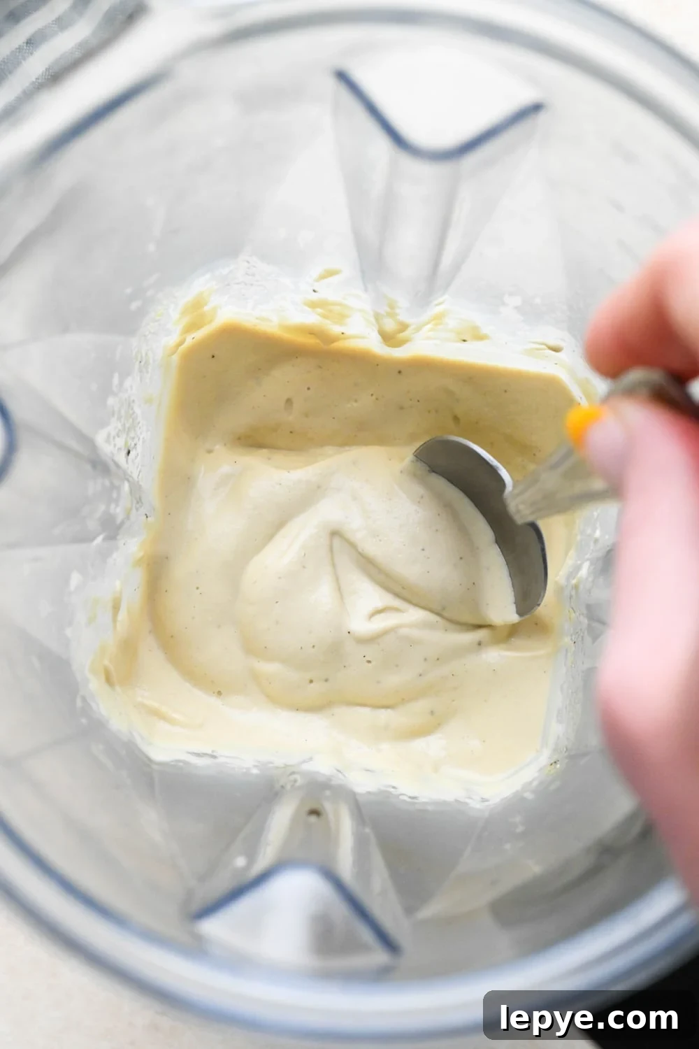 How to make dairy free smoked salmon dip: Cashew cream base in a blender container after blending to show thick creamy texture.
