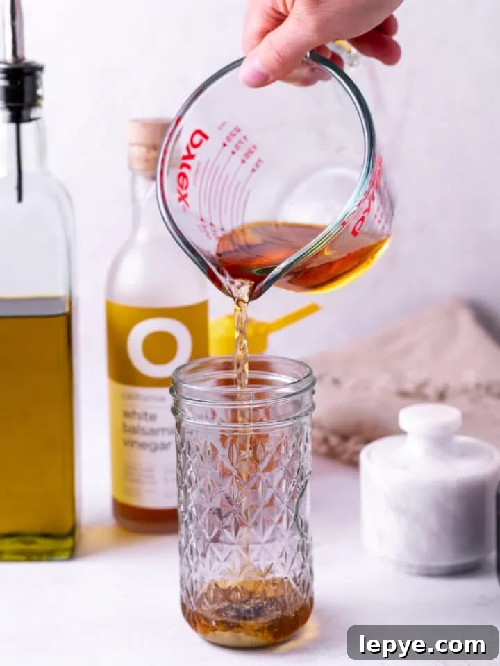 White Balsamic Vinaigrette Recipe: Tangy Salad Dressing with Herbs 5 hand pouring vinegar from a liquid measuring cup into a jar