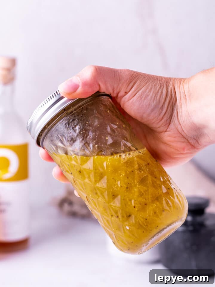 White Balsamic Vinaigrette Recipe: Tangy Salad Dressing with Herbs 8 hand shaking a jar of white balsamic vinaigrette