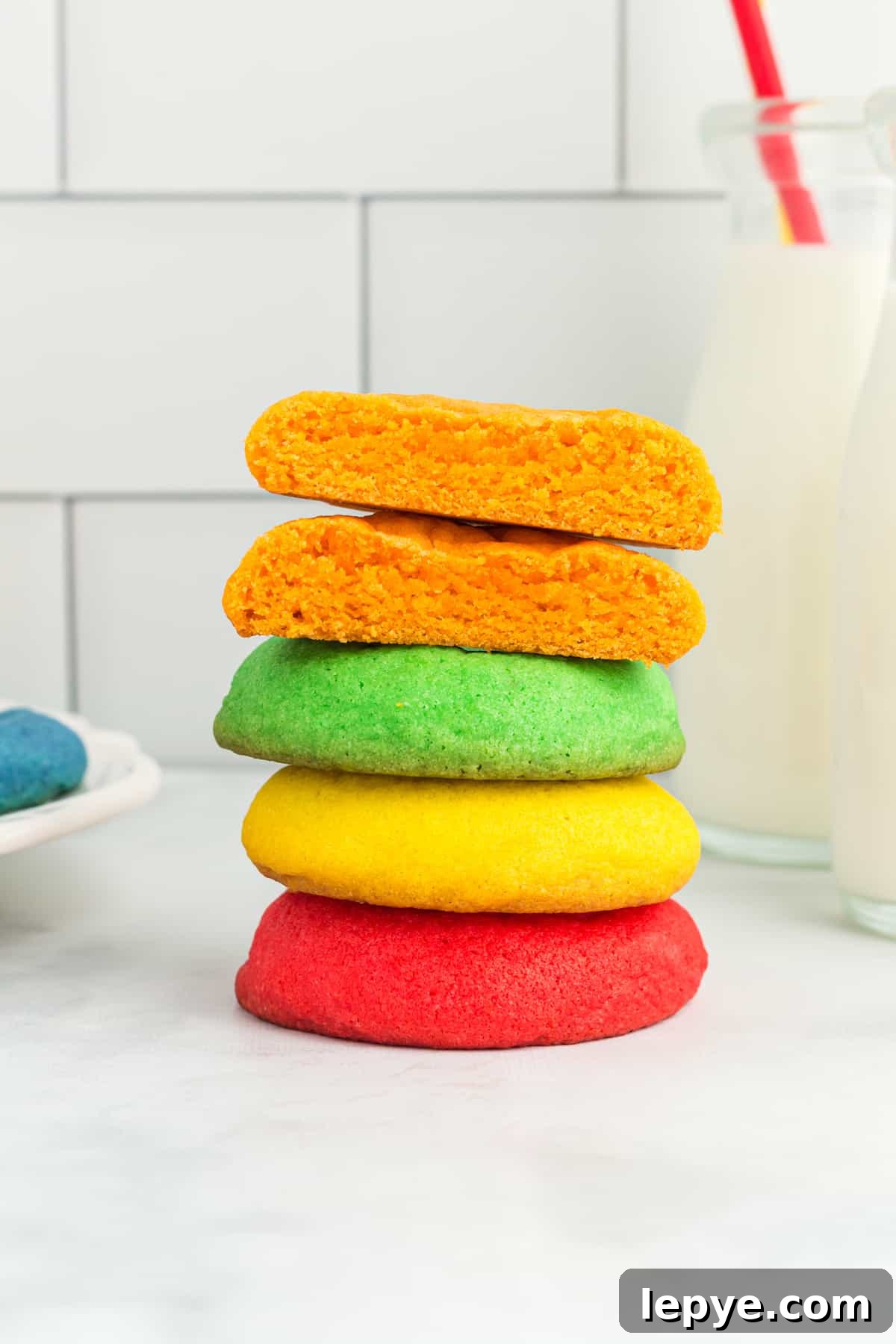 a halved orange jello mix cookie on top of a stack of red, yellow, and green cookies.