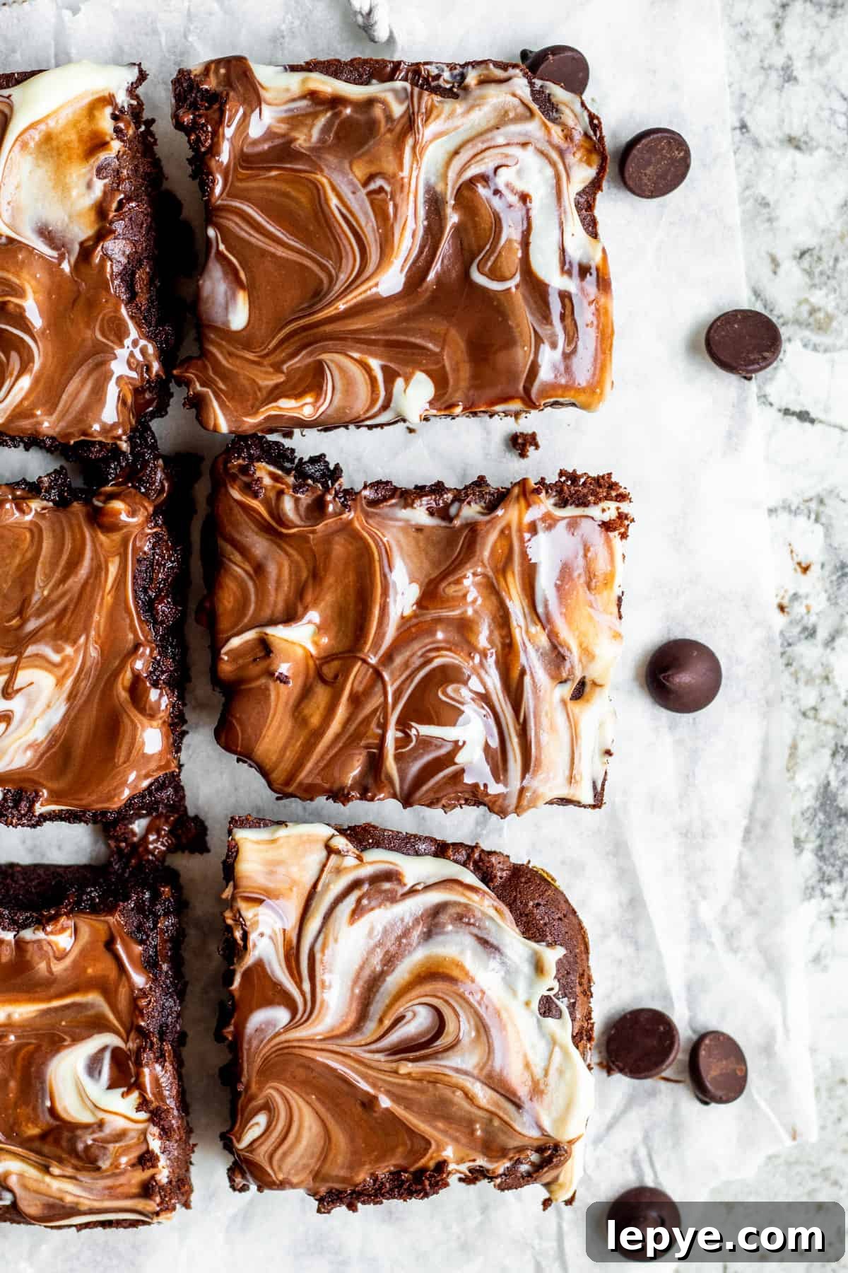 Gooey Chocolate Fudge Brownies with Rich Chocolate Drizzle 2 Overhead shot of brownies sliced on white parchment paper.