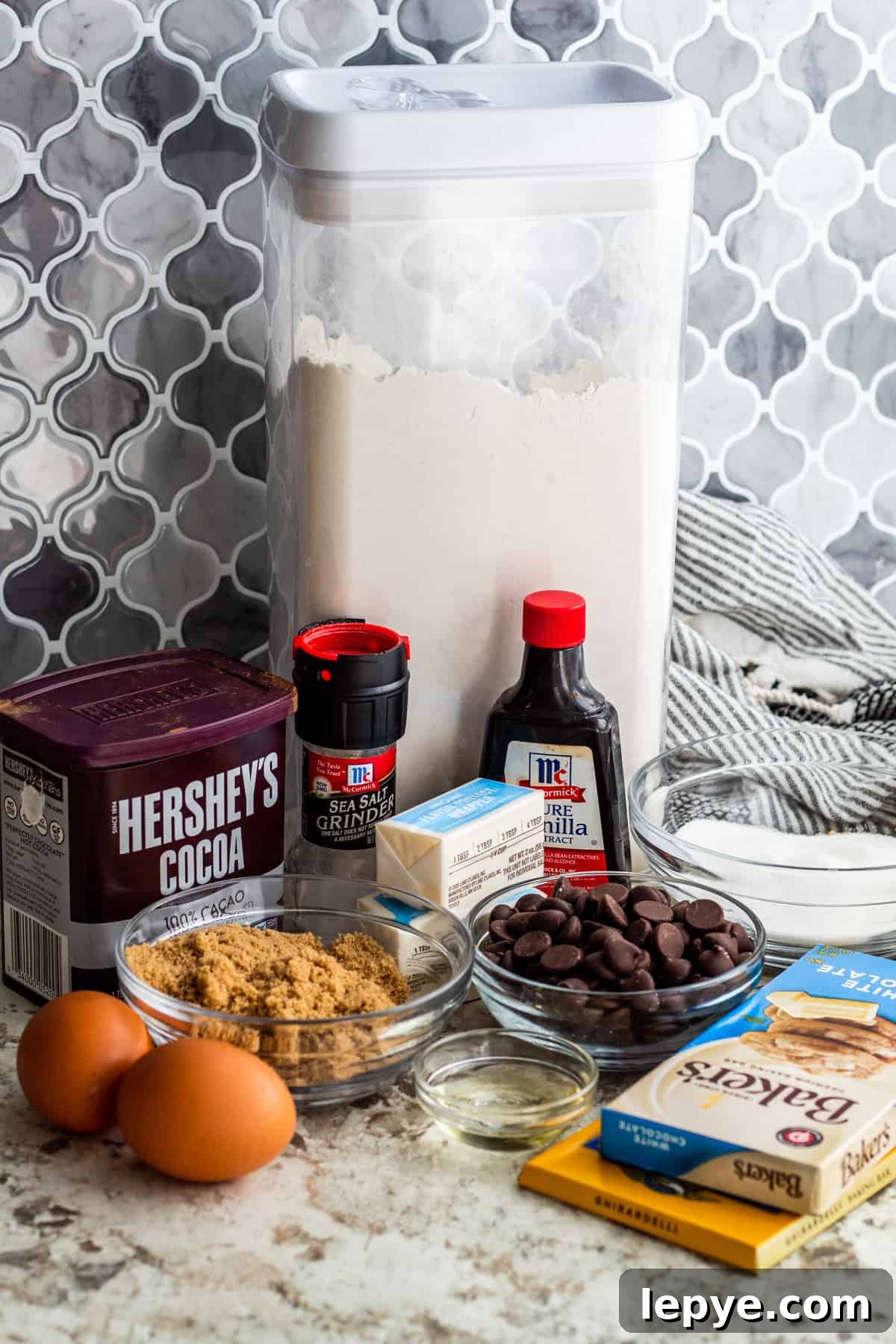 Gooey Chocolate Fudge Brownies with Rich Chocolate Drizzle 3 Brownie ingredients laid out on white counter in containers and small bowls.