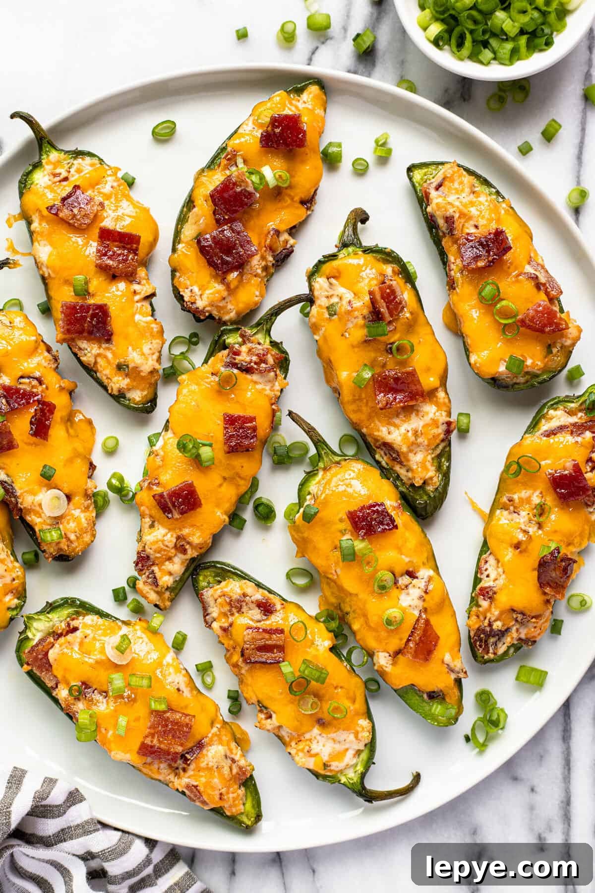 Smoked Jalapeño Poppers Recipe for Perfect Grill Parties 2 White plate with smoked jalapeno poppers garnished with sliced green onion.