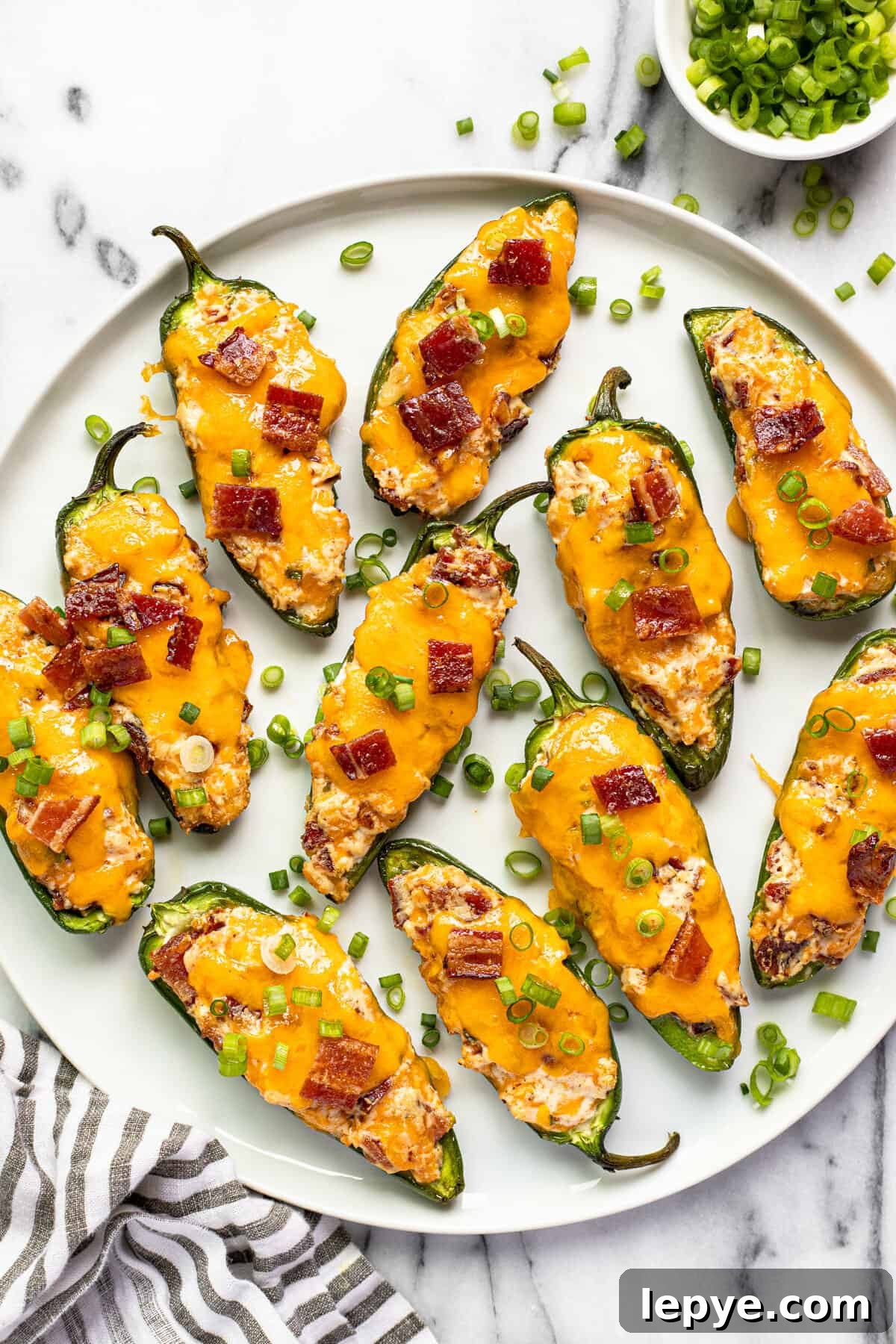 Smoked Jalapeño Poppers Recipe for Perfect Grill Parties 11 White plate with smoked jalapeno poppers garnished with sliced green onion.