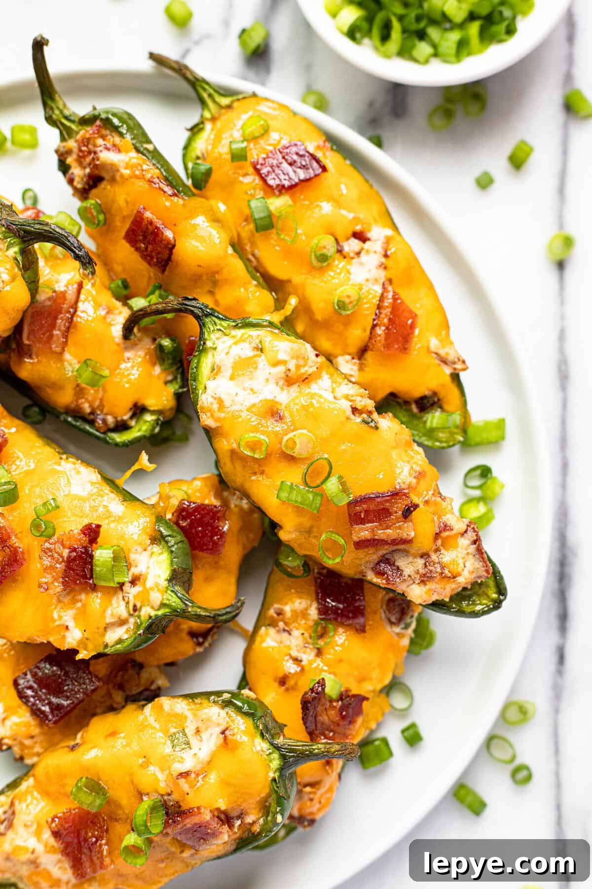 Smoked Jalapeño Poppers Recipe for Perfect Grill Parties 12 White plate with smoked jalapeno poppers garnished with sliced green onion.