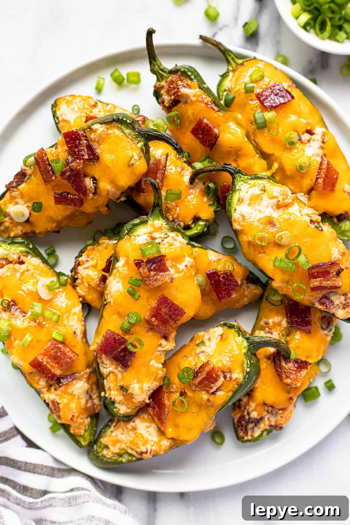 Smoked Jalapeño Poppers Recipe for Perfect Grill Parties 13 White plate with smoked jalapeno poppers garnished with sliced green onion.