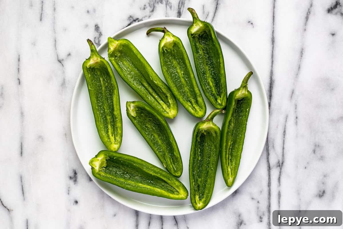 Smoked Jalapeño Poppers Recipe for Perfect Grill Parties 5 Halved jalapenos on a white plate.