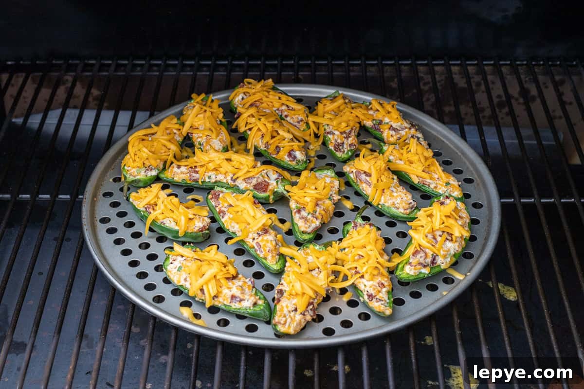 Smoked Jalapeño Poppers Recipe for Perfect Grill Parties 9 Jalapeno poppers on a pizza pan on a grill grate in the smoker.
