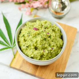 Cannabis-Infused Guacamole Recipe: Fast Homemade Pot Guac 10 A bowl filled with guacamole garnished with a cannabis leaf