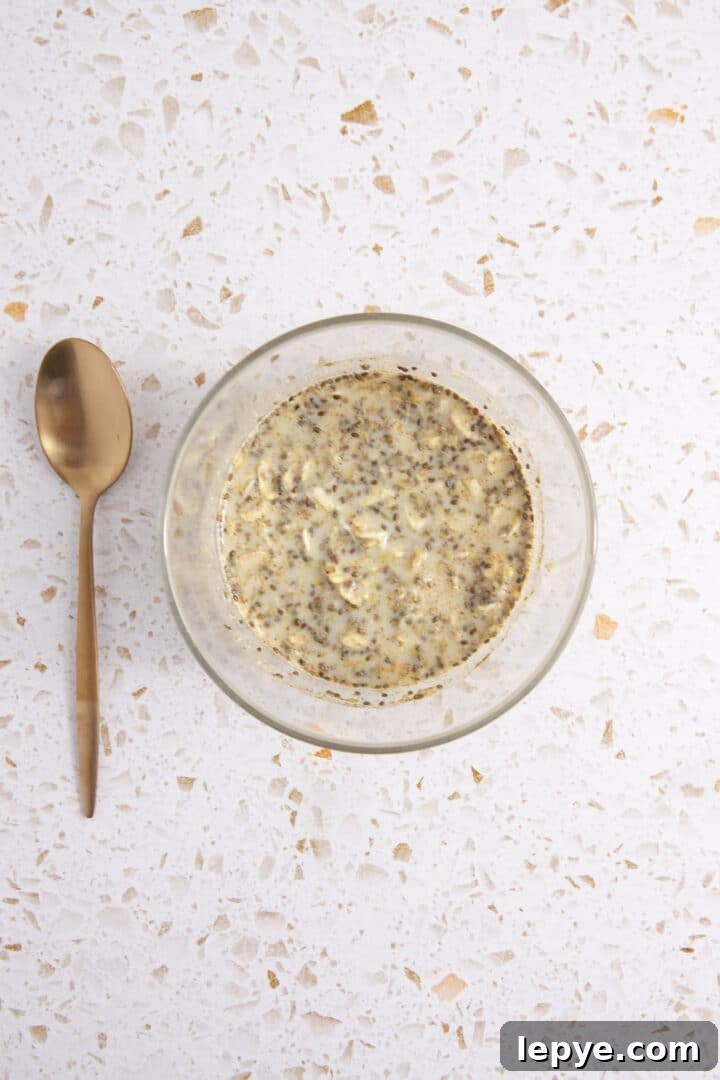 overnight oats mixed in a glass jar with a spoon sitting next to them