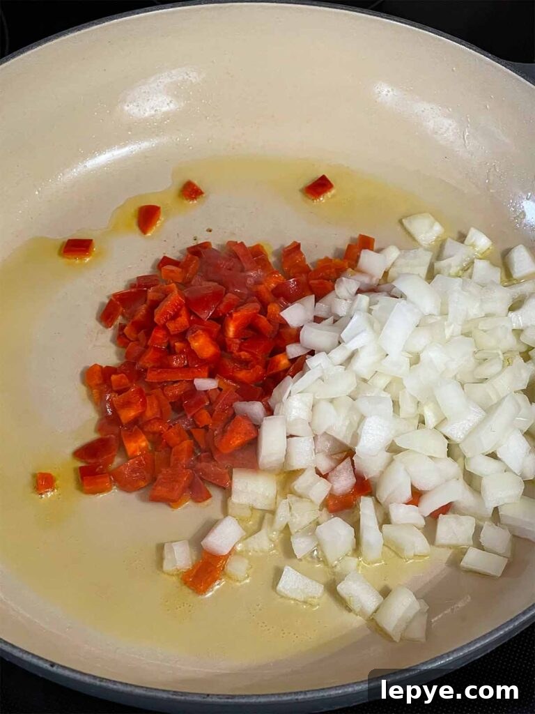 Onion and red bell pepper in a skillet.