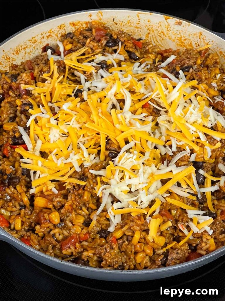 Adding cheese to the Mexican ground beef mixture.