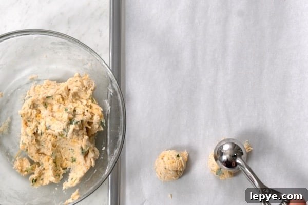 One-Bowl Garlic Cheddar Drop Biscuits Recipe 6 Scooping biscuit dough onto baking sheet pan lined with parchment