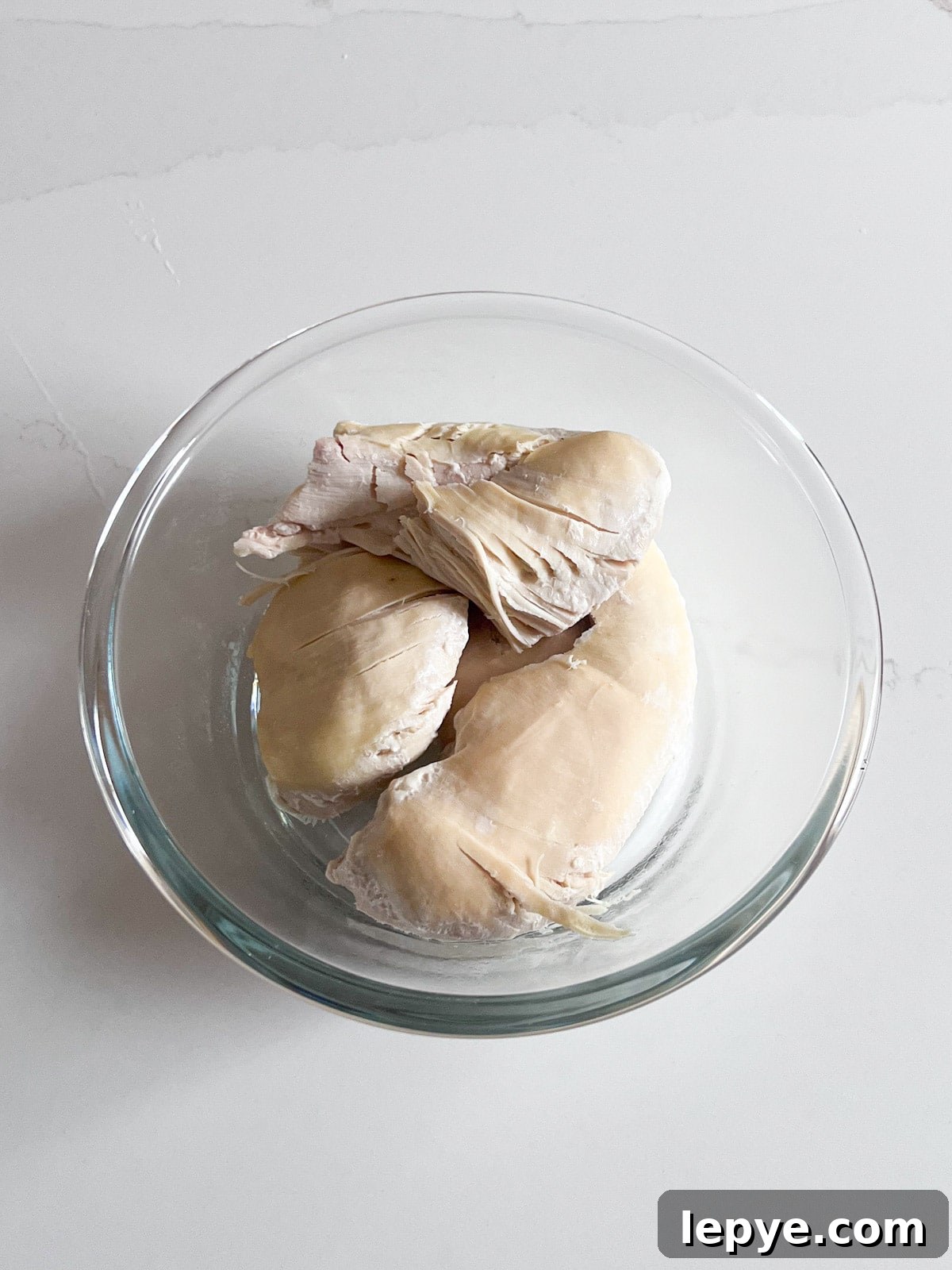 Shredded Chicken Recipes: Crockpot and Instant Pot Guide 4 Cooked chicken breasts in a glass bowl.