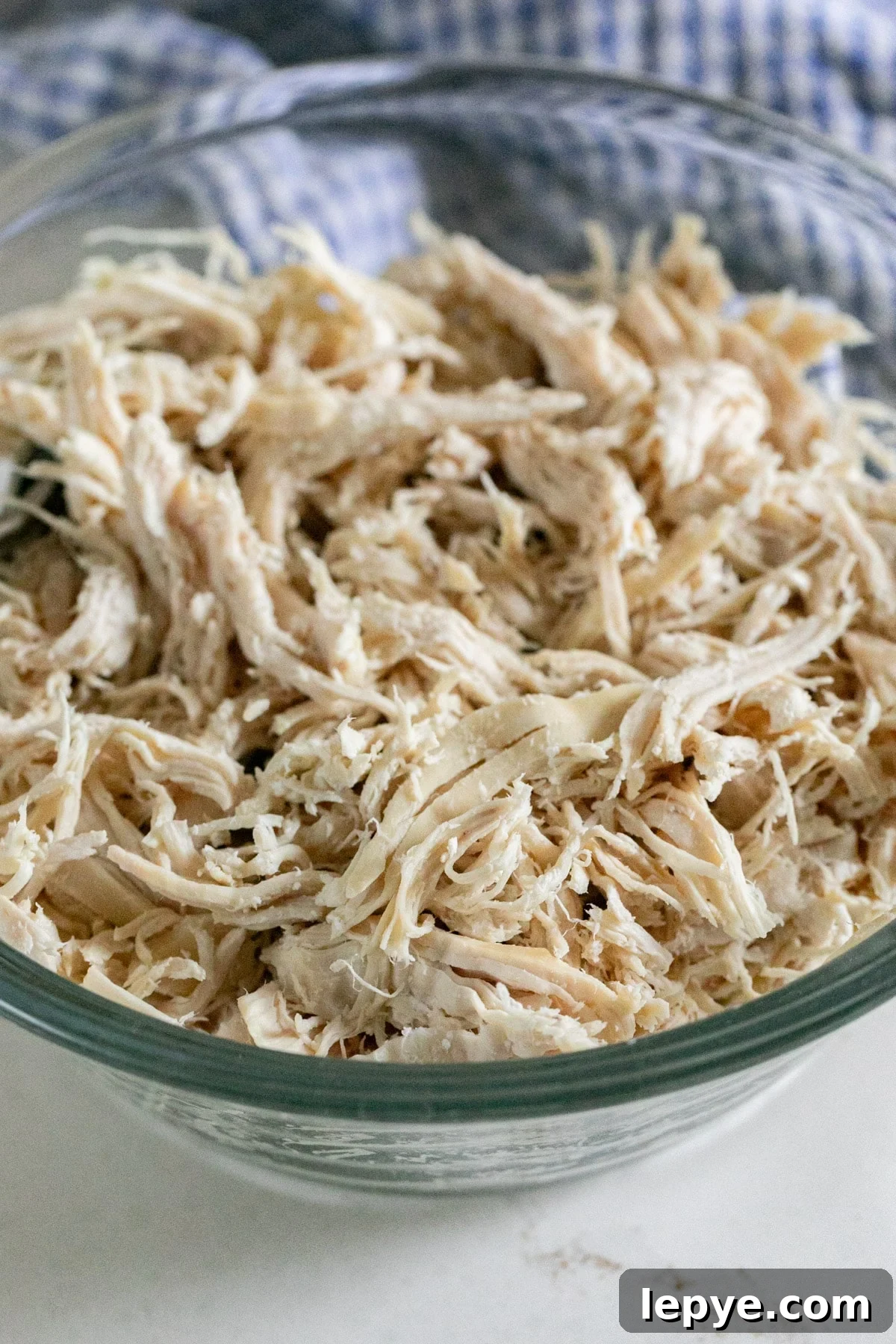 Shredded Chicken Recipes: Crockpot and Instant Pot Guide 6 A close up image of shredded chicken breast in a glass bowl.