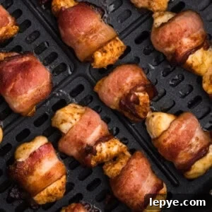 Crispy Bacon-Wrapped Chicken Bites Made in the Air Fryer 11 air fried bacon wrapped chicken bites in the basket of the air fryer.