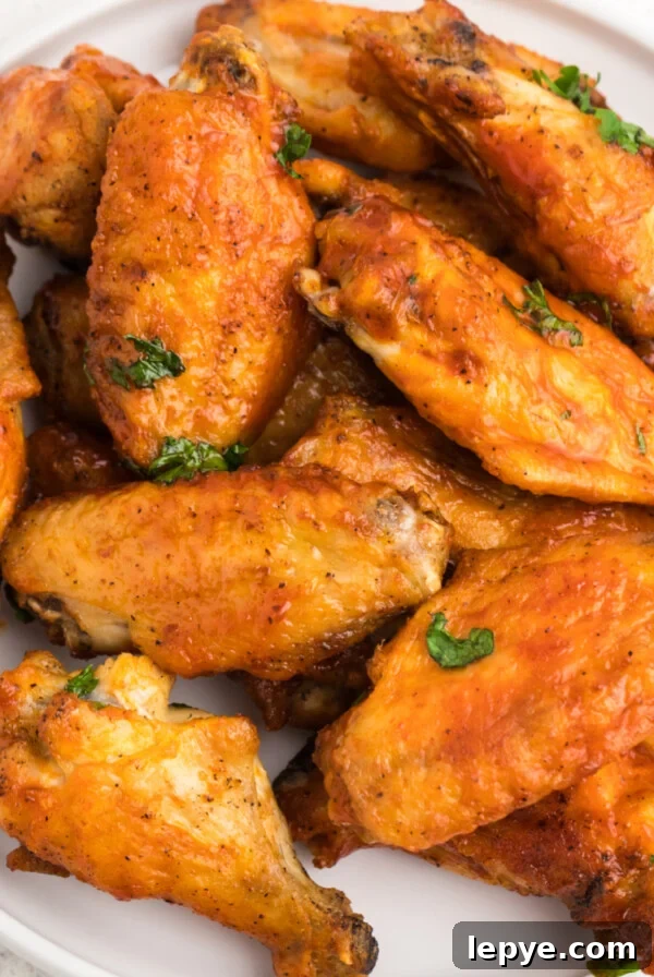 Crispy Bacon-Wrapped Chicken Bites Made in the Air Fryer 7 Crispy Air Fryer chicken wings on a white plate ready to serve.