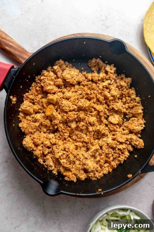 Seasoned tofu crumbles in a cast iron skillet.