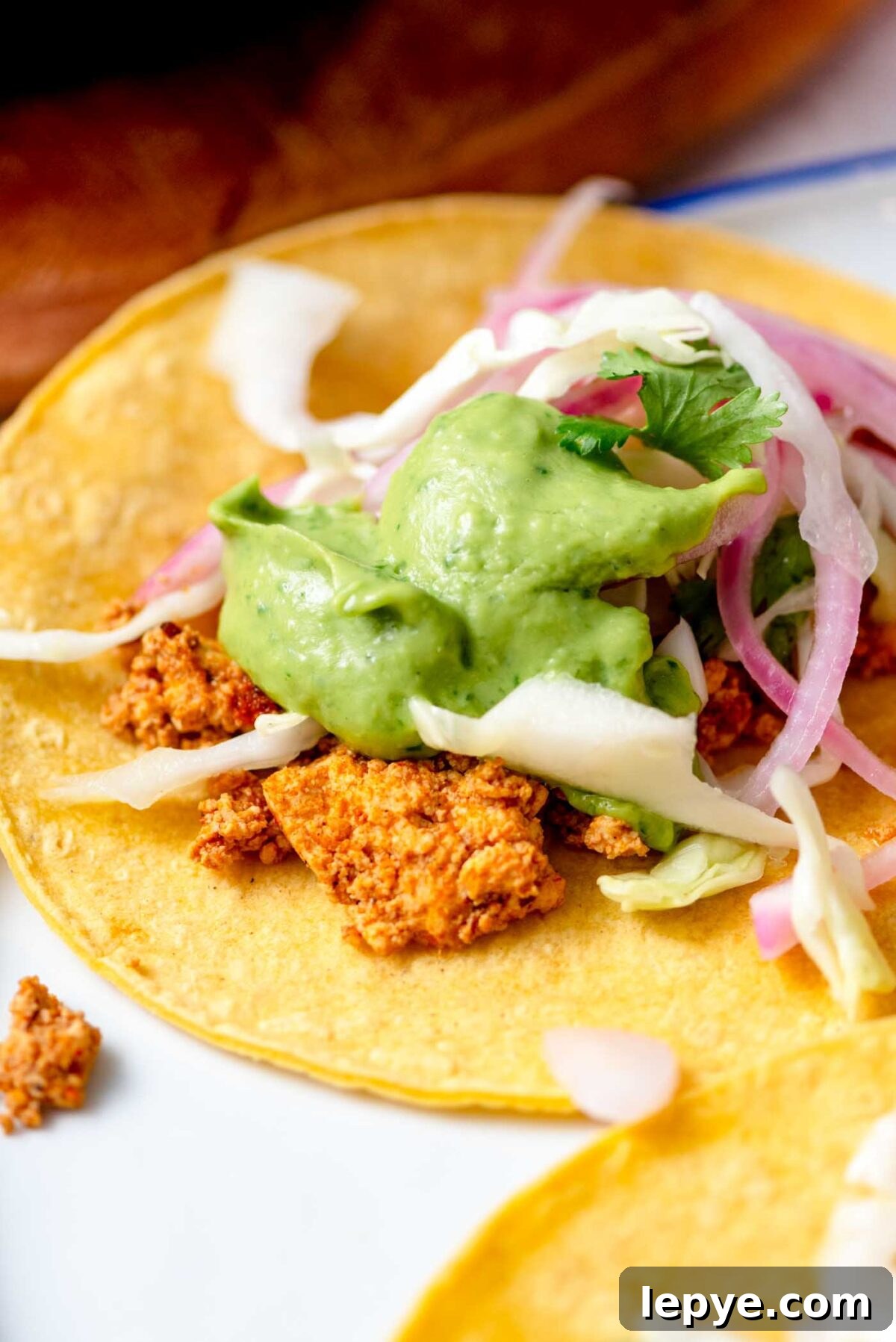 Tofu taco with avocado sauce, pickled onion and cabbage.