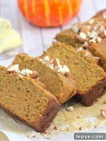 Protein pumpkin bread sliced and topped with almonds on a cutting board.