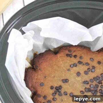 High-Protein Slow Cooker Banana Bread Recipe 13 Black slow cooker lined with parchment paper and high protein banana bread with chocolate chips in it.
