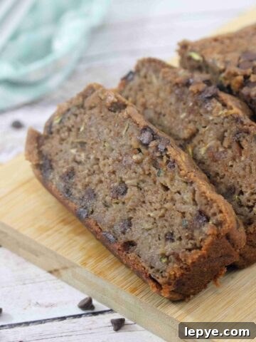Chocolate protein zucchini bread sliced on a cutting board with chocolate chips around it.