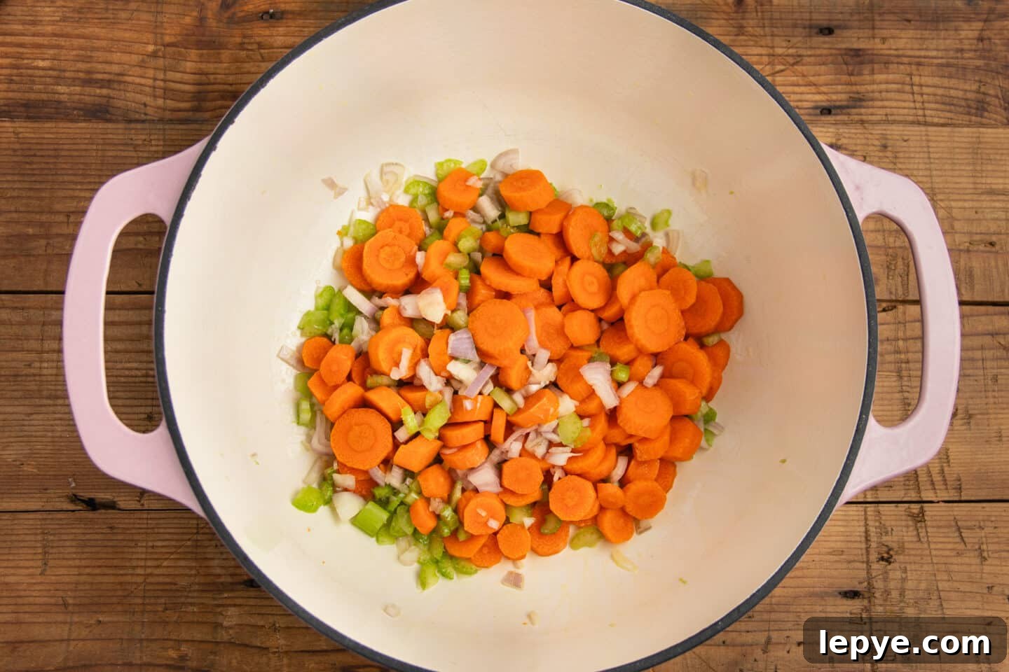 This is a picture of a large pot with carrots, onions and celery.