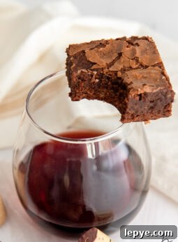 red wine brownie with a bite sitting on edge of stemless glass with red wine