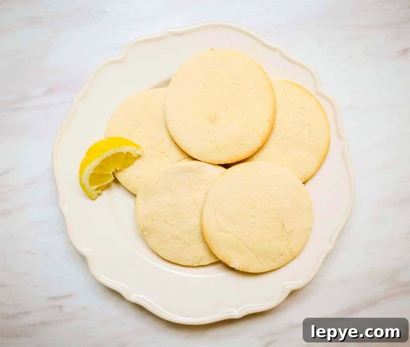 Southern Soul Tea Cake with Sweet Icing - Classic Recipe 4 Traditional Tea Cakes Recipe - Unfrosted Black folks’ tea cakes on a white plate with a lemon wedge, showcasing the soft, buttery texture of this traditional Southern dessert. Homemade soul food cookies by Shaunda Necole & The Soul Food Pot®.