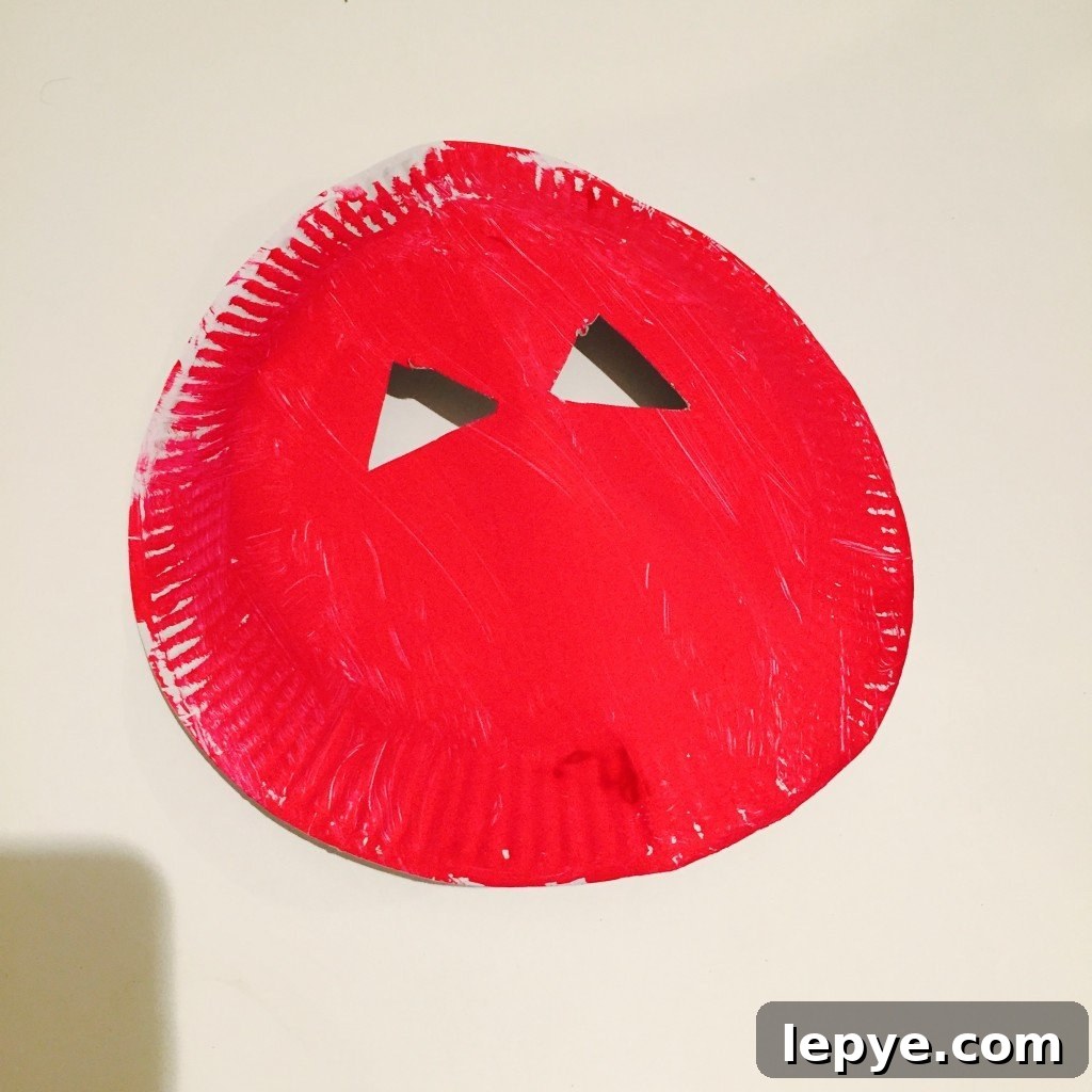 Chinese Dragon Mask Craft for Kids: Step-by-Step Paper Mask Tutorial 3 paper plate painted red with eye holes cut out in triangles