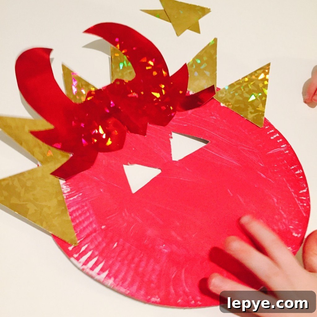 Chinese Dragon Mask Craft for Kids: Step-by-Step Paper Mask Tutorial 8 child sticking decorations onto a dragon mask craft