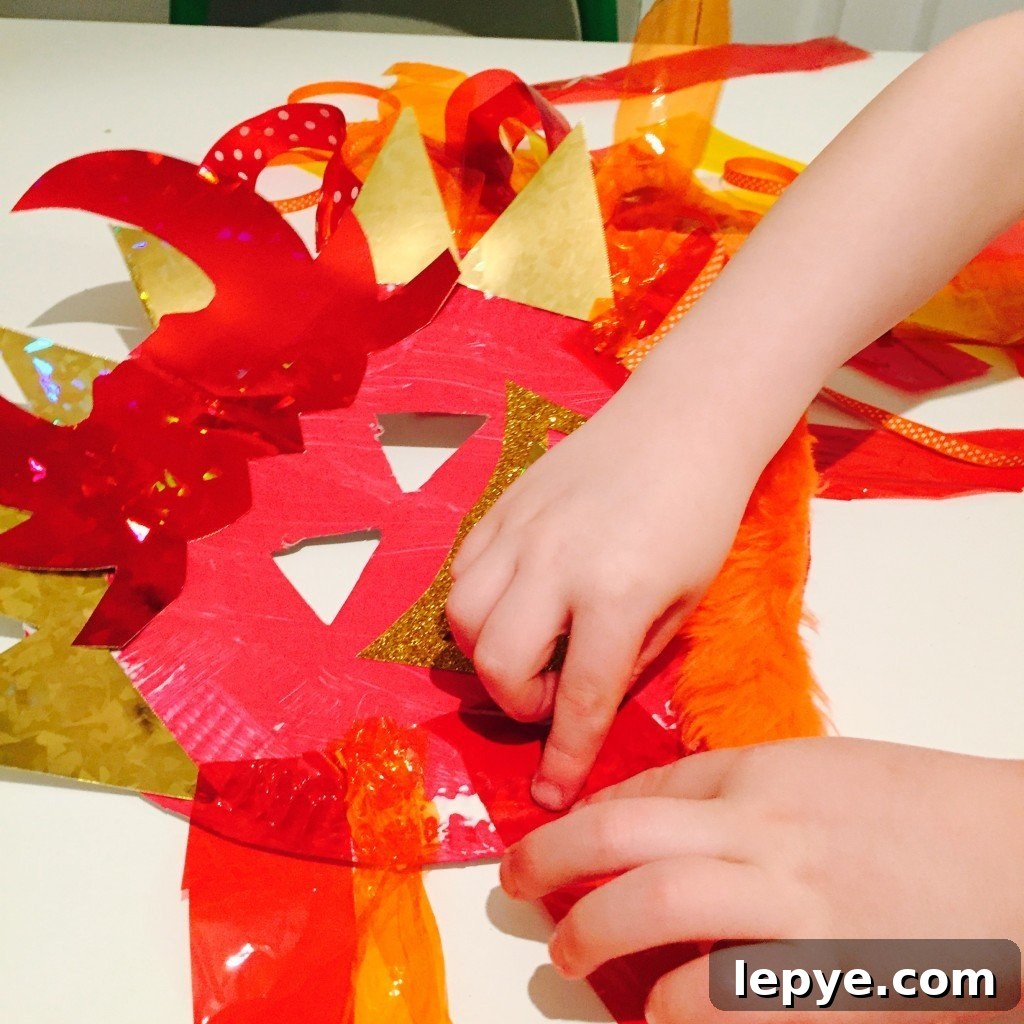 Chinese Dragon Mask Craft for Kids: Step-by-Step Paper Mask Tutorial 10 child sticking decorations onto a dragon mask craft