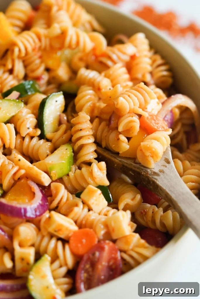 supreme pasta salad with a wooden spoon taking a spoonful
