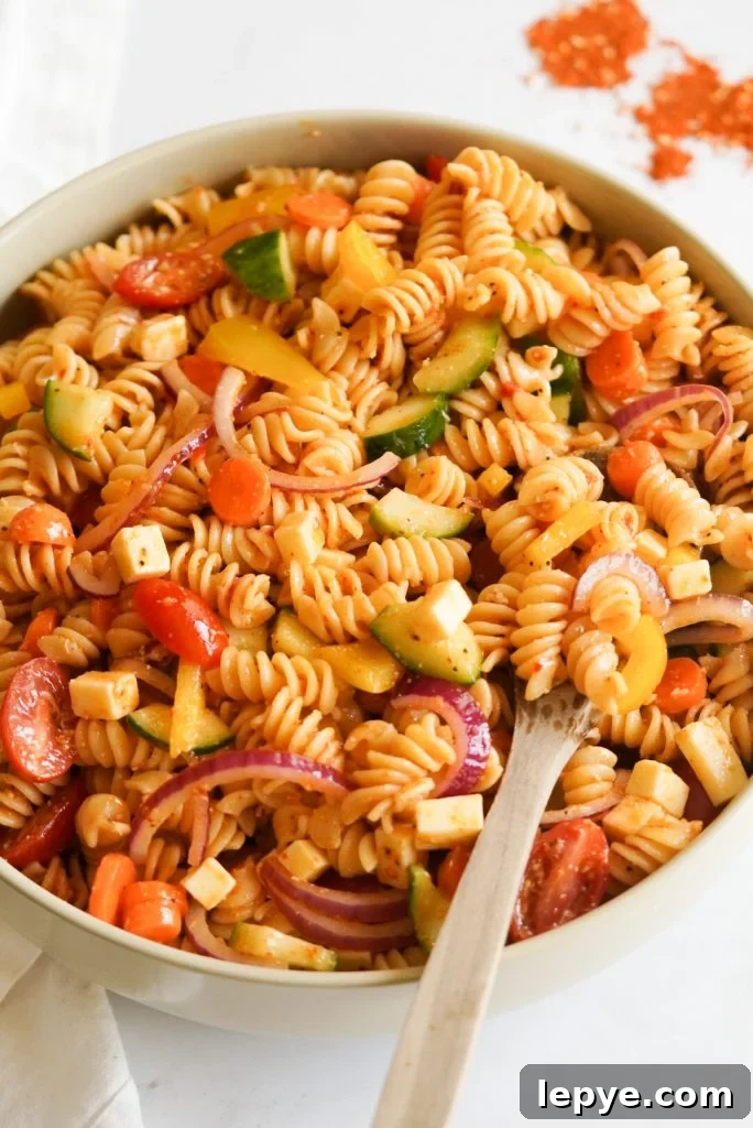 pasta salad in a large bowl with a wooden spoon