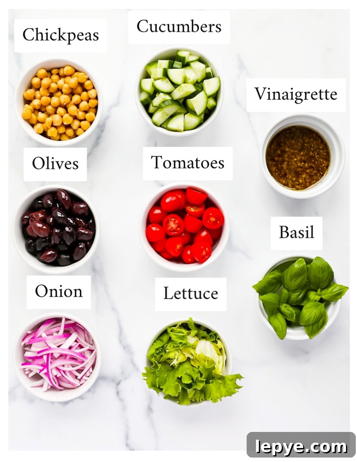 Labeled ingredients including: chickpeas, cucumbers, olives, tomatoes, vinaigrette, basil, lettuce, and onion