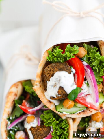 Three vegetable gyros stacked on top of each other and wrapped in white parchment paper.