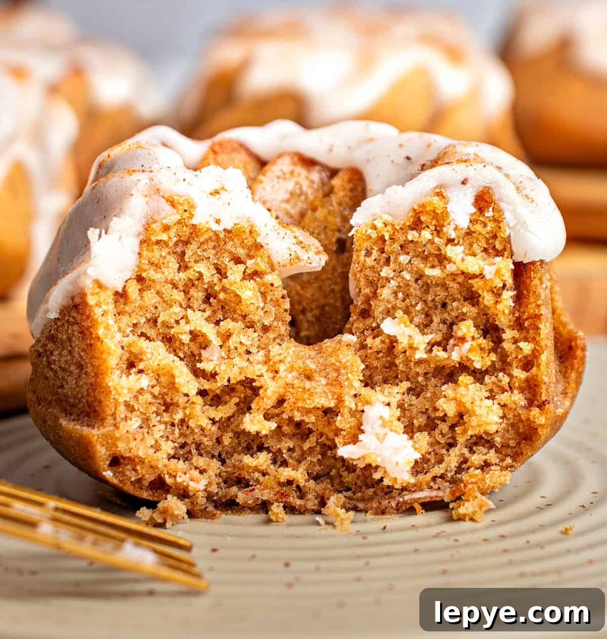 Half a glazed pumpkin mini bundt cake on a gray plate.